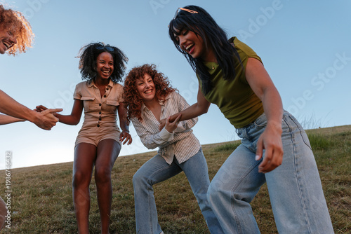Diverse friends laughing and holding hands on hillside