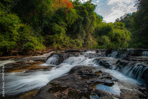 A waterfall cascading down rocks in the forest amidst nature.