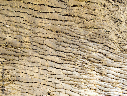 Fotografie Texture of dry soil with deep horizontal cracks creates a unique natural pattern
