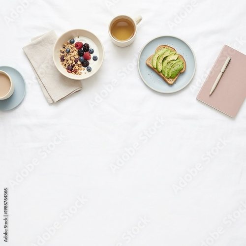 Minimalist breakfast flat lay on white sheets with avocado toast, yogurt bowl, and journal