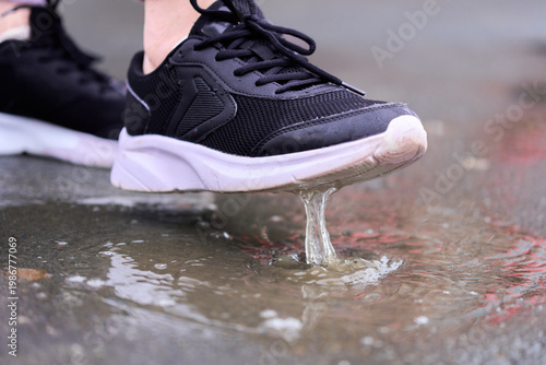 Foto Person walks in rain and splashes water with shoes on wet pavement during a clou