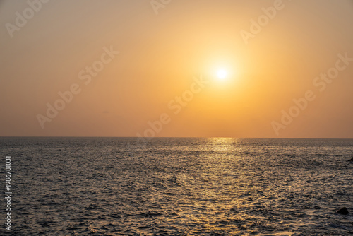 Sunset at the sea. The sun is setting in golden haze over the calm sea.