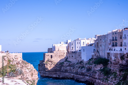 The dramatic cliffs of Polignano a Mare overlooking the Adriatic Sea, where whitewashed houses rise above crystal-clear waters along the rugged coastline.