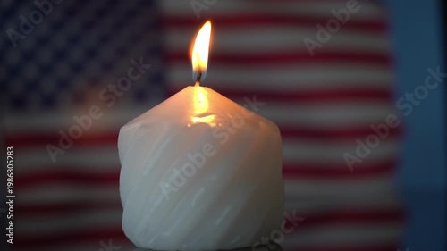 The candle is lit in memory of the deceased citizens of the United States of America. Mourning is a loss. The US flag is blurred in the background. High quality FullHD footage