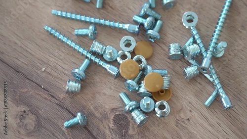 Bolts nuts plugs for furniture assembly on a wooden background close-up. High quality FullHD footage