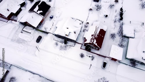 A view from a quadcopter of several residential buildings in winter, flying around houses and cars parked near cottages from above. High quality 4k footage