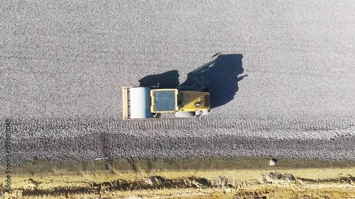 A heavy roller is rammed into the gravel foundations during the construction of a new road. View from above. Road construction machinery. High quality 4k footage