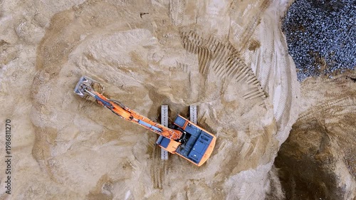 An excavator is engaged in moving soil in a sand quarry top view from a quadcopter. Excavation with the help of heavy construction machinery in quarries, mining and extraction of kh minerals. High