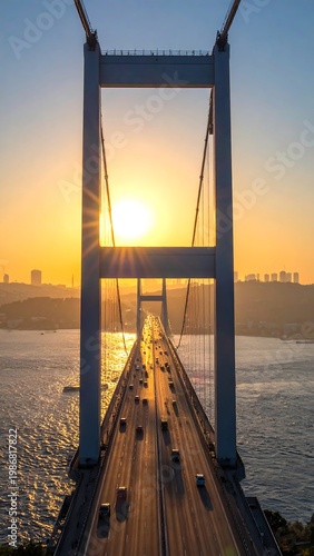 A suspension bridge stretches over a body of water at sunset
