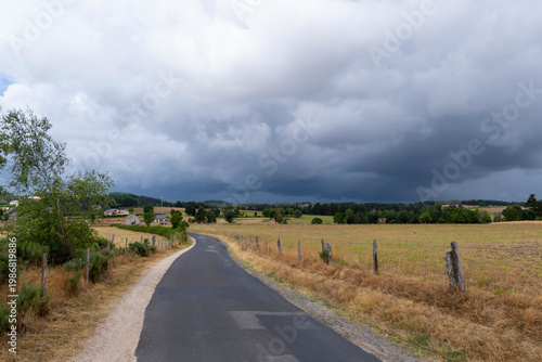 GR65 pilgrim trail crossing the Aubrac plateau, yellowed grass and dramatic cloudy sky, France