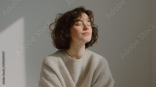 person sitting peacefully with eyes closed, soft light, neutral colors, minimal environment, slow living concept