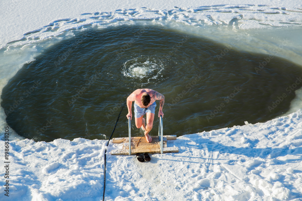 Fototapeta premium Overhead view man swimming in ice hole, cold plunge therapy, winter lake immersion, biohacking, snow texture, sun, top view, conceptual