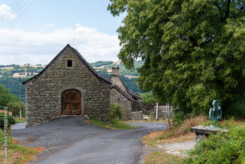 Ancient stone building and old bronze cross monument in a historic village, Aveyron, France