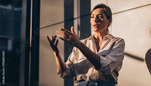 A woman gesturing with her hands in a modern setting.