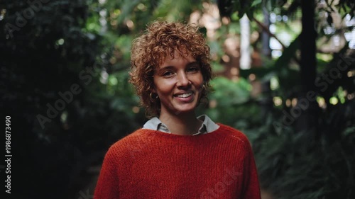 Young woman portrait smiling in lush green urban garden, happy connected with nature