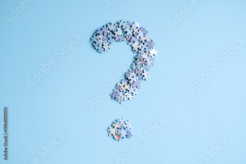 Puzzle pieces arranged in shape of large question mark on light blue background. Global conflict risks, geopolitical instability analysis, world order transition.