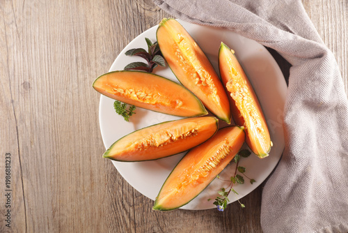 Fotografía Top View of Fresh Cantaloupe Melon Slice with Mint on White Plate