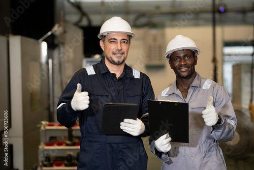 Thump up two engineer working with tablet computer with machine background at auto parts factory