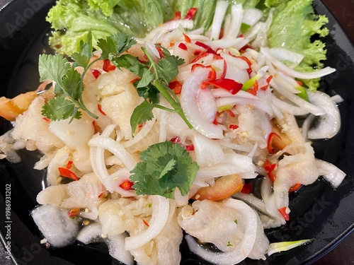 Authentic Thai chicken feet salad with chili, lime, and fresh herbs, offering a tangy, spicy, and crunchy texture.