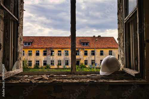 White Hard Hat on Windowsill of Abandoned Building with Broken Glass and Peeling Paint
