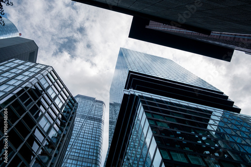 Looking upward through urban glass office architecture to a skyline of skyscraper towers in bankenviertel frankfurt germany under soft light