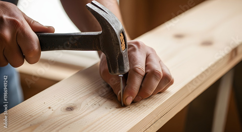 Handyman's close-up shot of a person using a hammer to hit a nail into a wooden plank, demonstrating DIY home improvement and construction skills