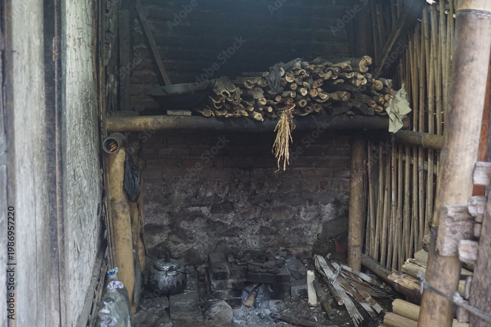 Fototapeta premium Rustic bamboo cooking area with brick hearth, pots, firewood, and bamboo shelves in a traditional rural setting.