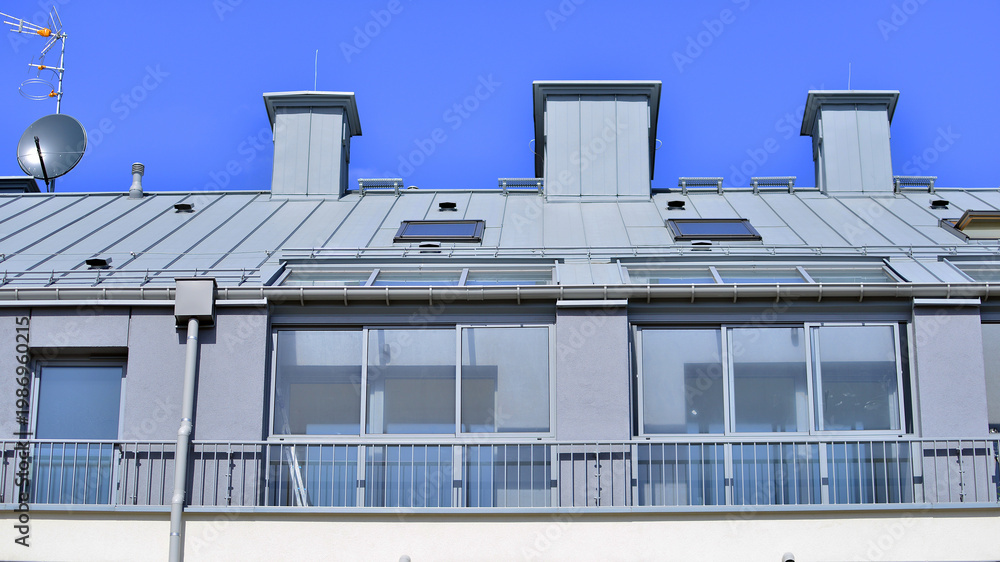 Fototapeta premium Modern residential structure showcasing a contemporary design with sloped roof, big windows and balconies.