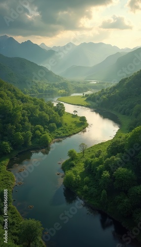 Aerial view of green valley with winding river and misty mountains. Sun rays pierce clouds over lush forest and calm water surface. Serene natural landscape unfolds.