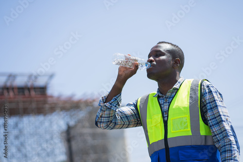 african american construction worker drinking water to stay hydrated on site