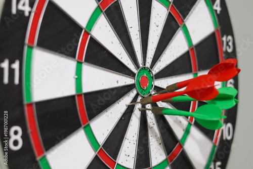фотографія Red and green darts stuck in a professional dartboard, symbolizing success, accuracy, and hitting the target in business or sports