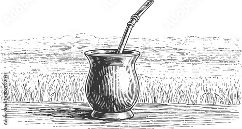 Traditional south american yerba mate cup with metal straw on wooden surface by grass field