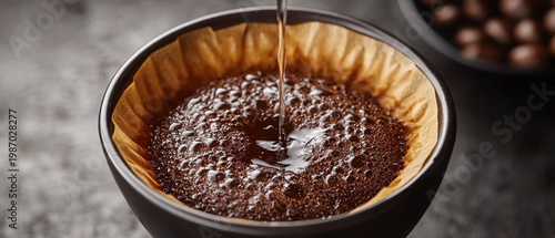 Hot coffee pours into the filter above a cup, releasing its aroma and providing the perfect backdrop for a coffee shop or morning rituals.