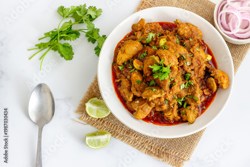 Authentic Indian Chicken Curry with Coriander Garnish Served in White Bowl on Rustic Background