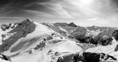 Snowy mountain landscape with clear sky and sun at midday, showcasing peaks and valleys in the distance. Tatra Mountains. Poland. Zakopane