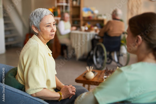 Fotografija Senior Asian woman receiving support from female caregiver in nursing home, disc