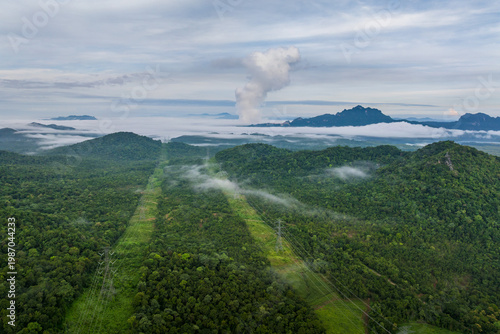 Aerial view Transmission tower in the green forest on a beautiful morning. Energy and environmental concept. High-voltage power poles Lampang, Thailand.
