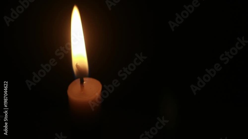 A macro shot of a flickering candle flame against a dark background, conveying a warm and cozy ambiance, loopable, looping