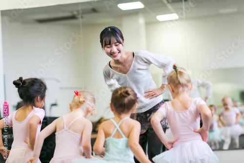 スタジオで子供たちににバレーのレッスンをする若い女性