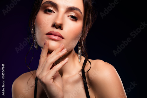 Stunning young woman posing with charming confidence against a dark background, showcasing luxury and fashion style