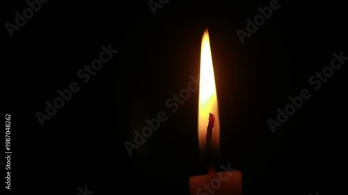 A close-up macro shot of a flickering candle flame against a dark background, looping, looapble, copy space