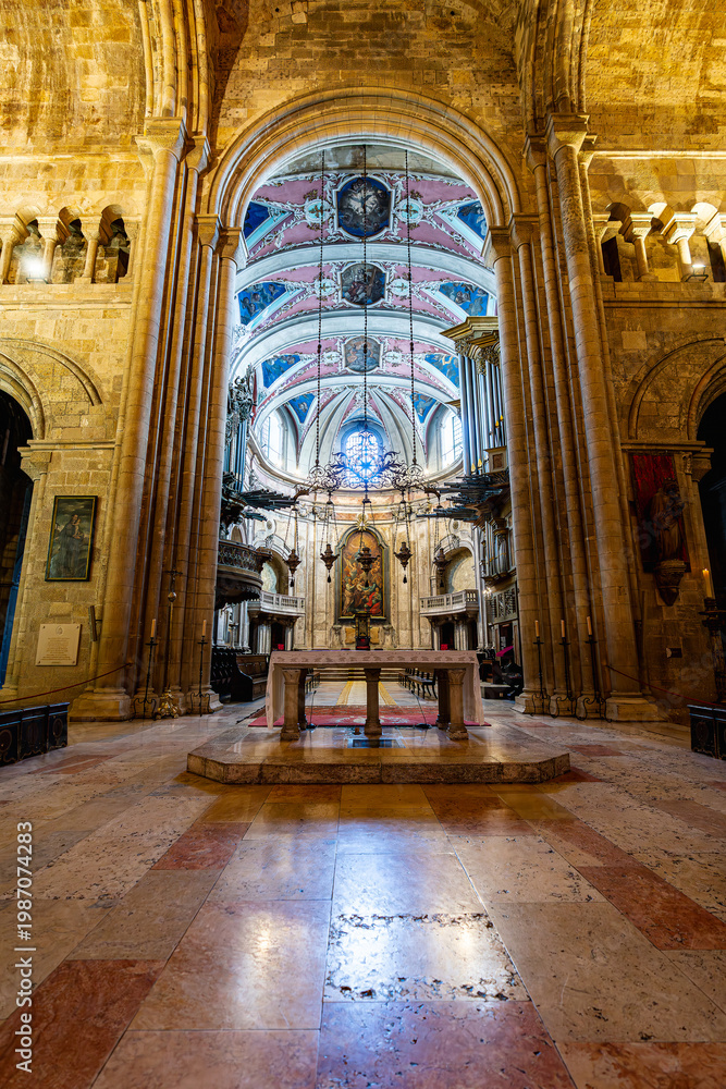 Fototapeta premium Historic cathedral interior with stone arches altar and decorative painted ceiling symmetrical perspective religious architecture and spiritual atmosphere in Lisbon