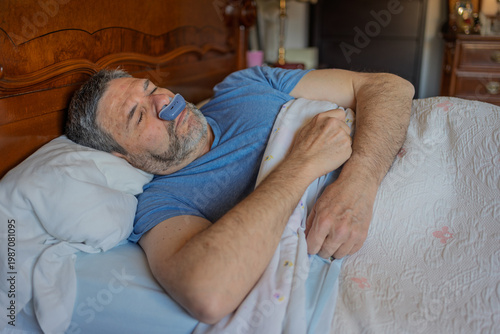 Man peacefully asleep, using a nasal dilator for better breathing, decreased snoring, and to avoid sleep apnea