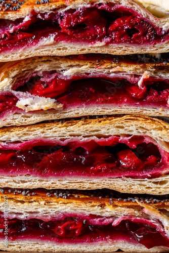 Closeup of stacked cherry strudel slices with flaky layers and poppy seeds topping rich fruit filling ideal for bakery dessert food photography and menu concept
