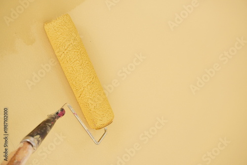 Paint roller applying yellow paint to a wall
