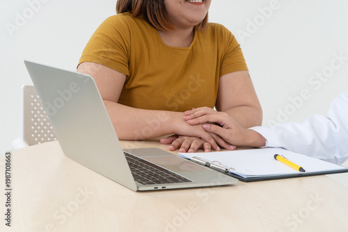 Consultation and Care: A close-up view capturing the moment of empathy and support between patient and medical professional during a consultation. A laptop and documents are placed on a desk.
