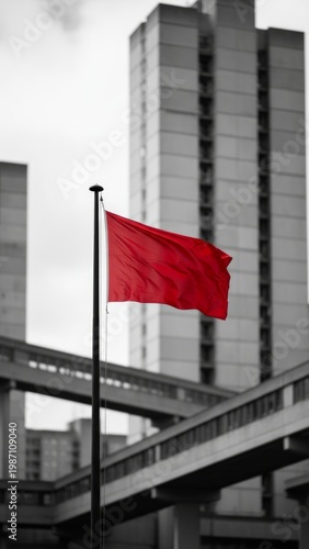 Red Flag Waving Against Urban High-Rise Buildings With Monochrome Background And Protest Symbolism