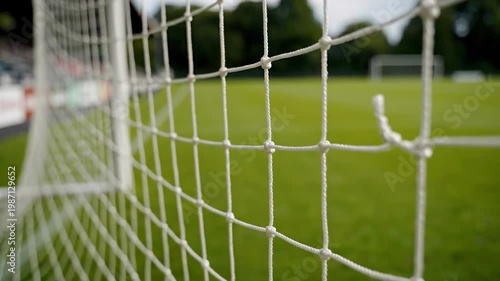 Football Net Perspective: A close-up view of a pristine football net, stretching across the goal, providing a fresh perspective on the lush green field beyond. 
