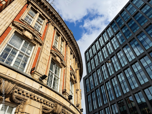 Contrast between historic stone facade and modern glass office building in Manchester, UK showcasing urban architecture and design