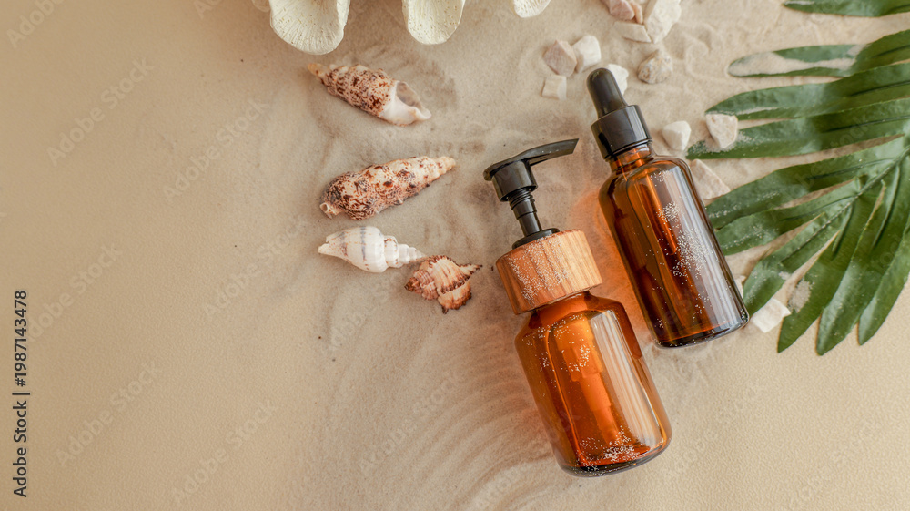 Fototapeta premium Elegant amber bottles on sandy beach with seashells and green leaves